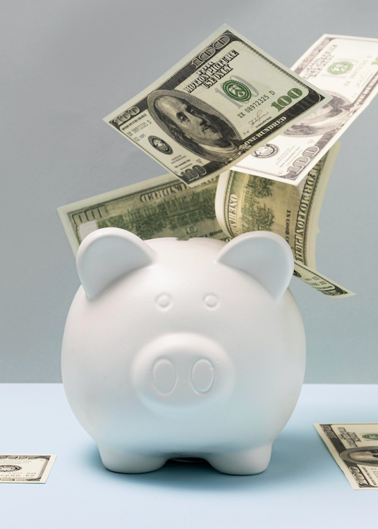 money in piggy bank Cash going into a white piggy bank.